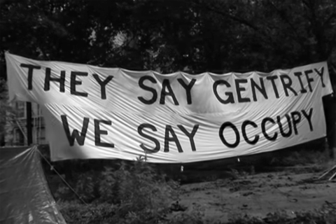 Black and White screenshot from the video. Banner that says 