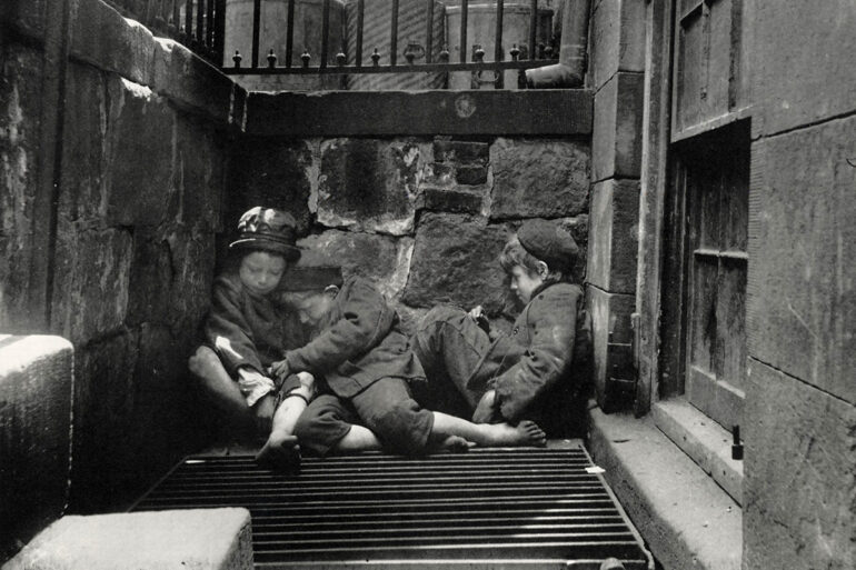 Black and white photograph depicting 3 children sleeping outside